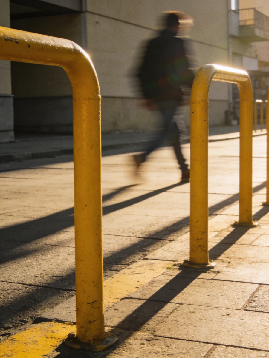 Row of bright yellow steel safety bollards installed along a storefront curb
