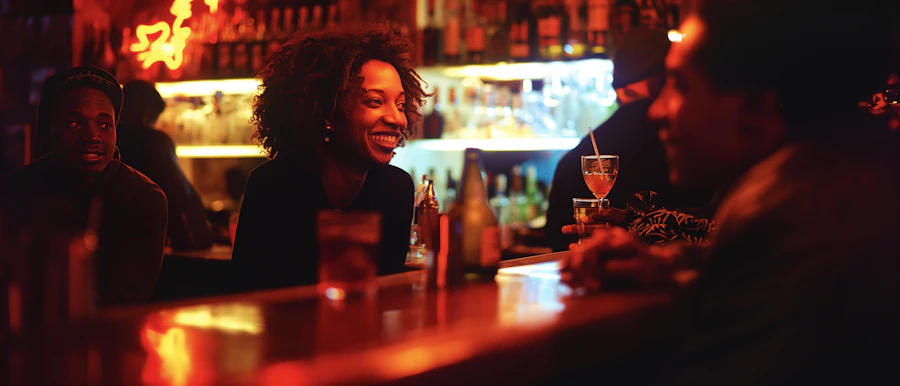 Patrons seated at a bar counter beneath string lights